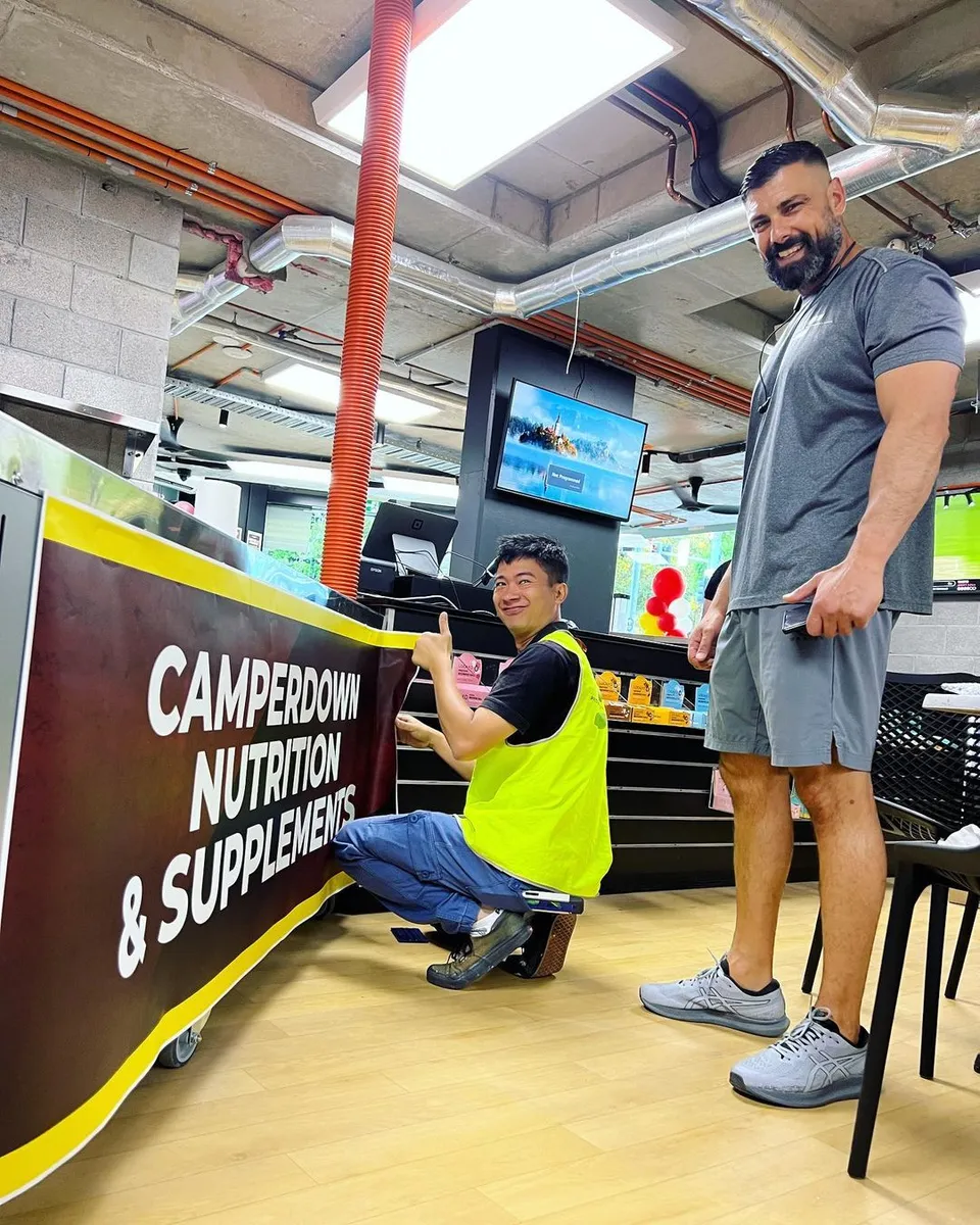 Staff and owners at the Camperdown Nutrition store front sign